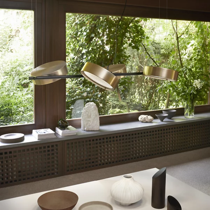 The Berlin Linear Suspension from Oluce in matte black with anodized brass in a dining room.