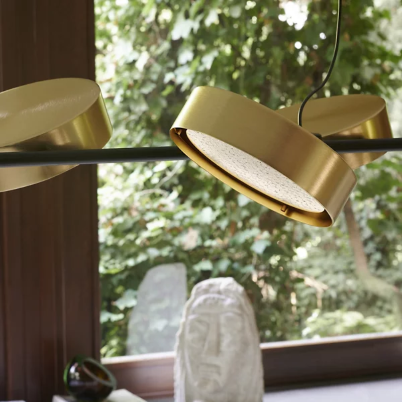 The Berlin Linear Suspension from Oluce in matte black with anodized brass in a living room.