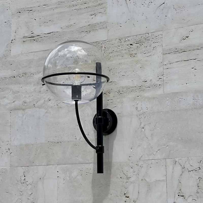 The Lyndon Outdoor Wall Sconce from Oluce in an outdoor lounge.