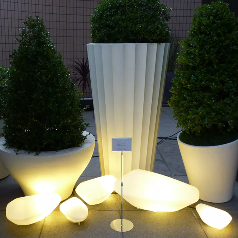 The Stones Outdoor Lamp from Oluce in a garden.
