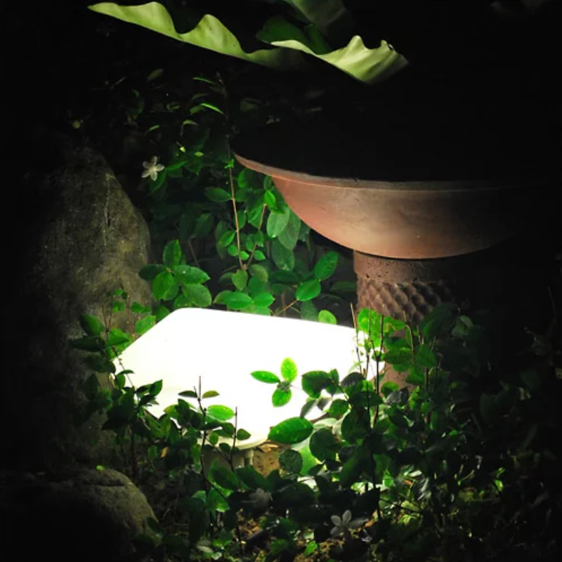 The Stones Outdoor Lamp from Oluce beside a plant pot.