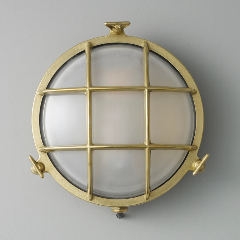 The medium Brass Bulkhead Outdoor Wall Sconce from Original BTC in polished brass in a studio.
