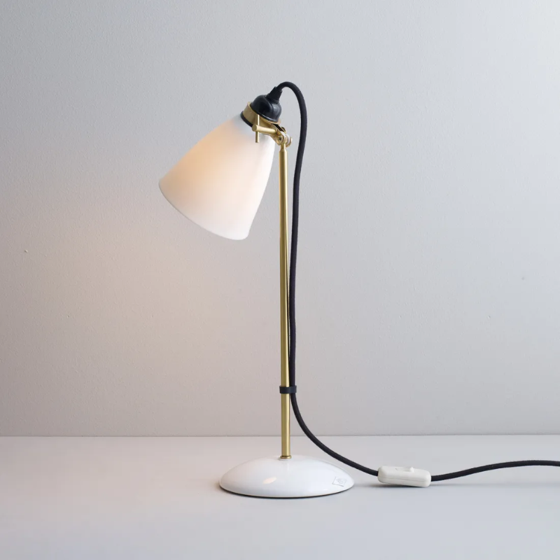 The Hector 30 Table Light from Original BTC with a black cable in a studio from an angle turned on.