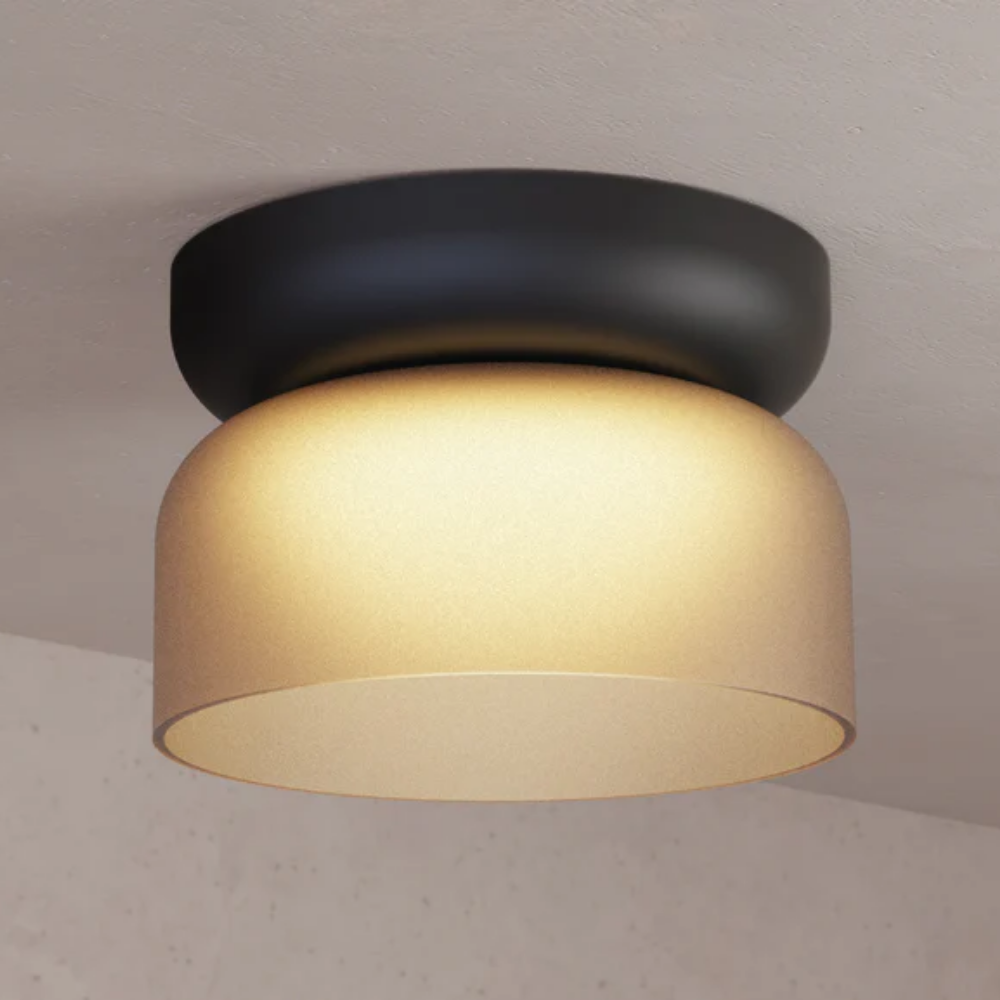The Totem Mini Flush Mount by Pablo Designs with an etched amber shade and black base in a family area. all-groups