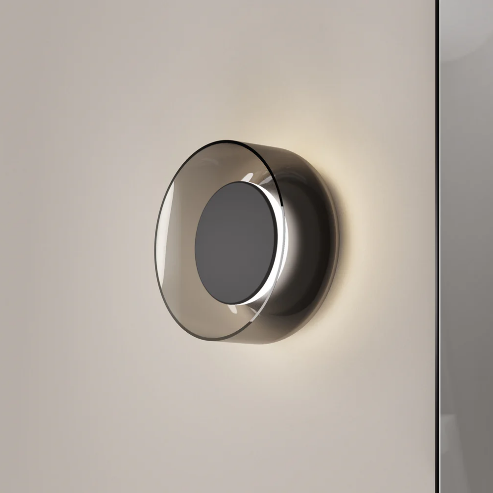 The Totem Sconce by Pablo Designs in Black / Black / Smoke turned on in a living room. all-groups