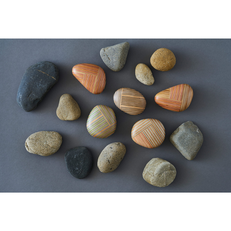 The various Koishi Paperweights from Plywood Laboratory in a lifestyle shot with pebbles. all-groups