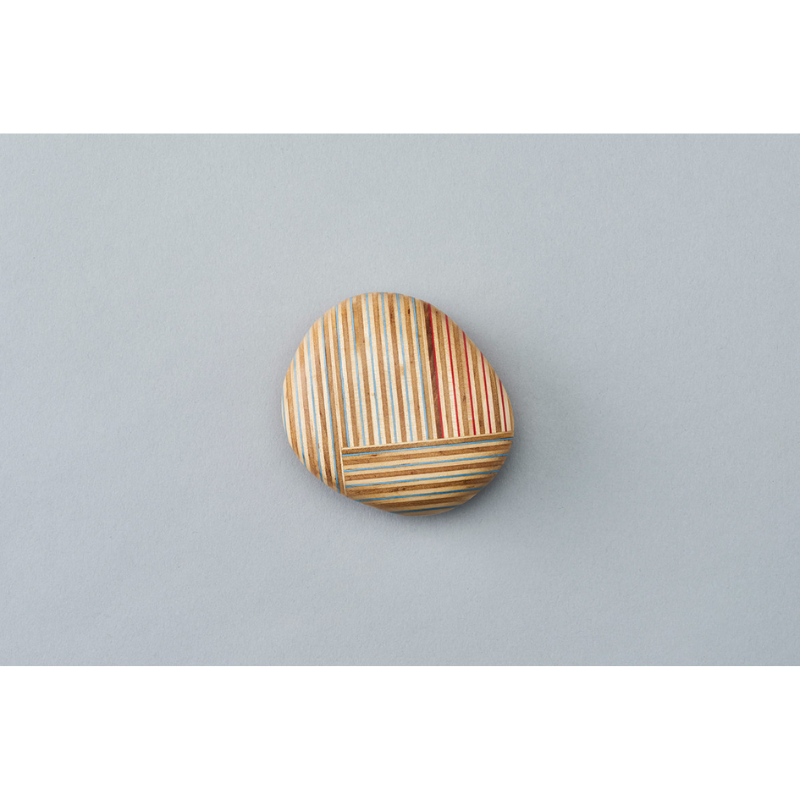 The Koishi Paperweight from Plywood Laboratory square shape in blue green within a studio.
