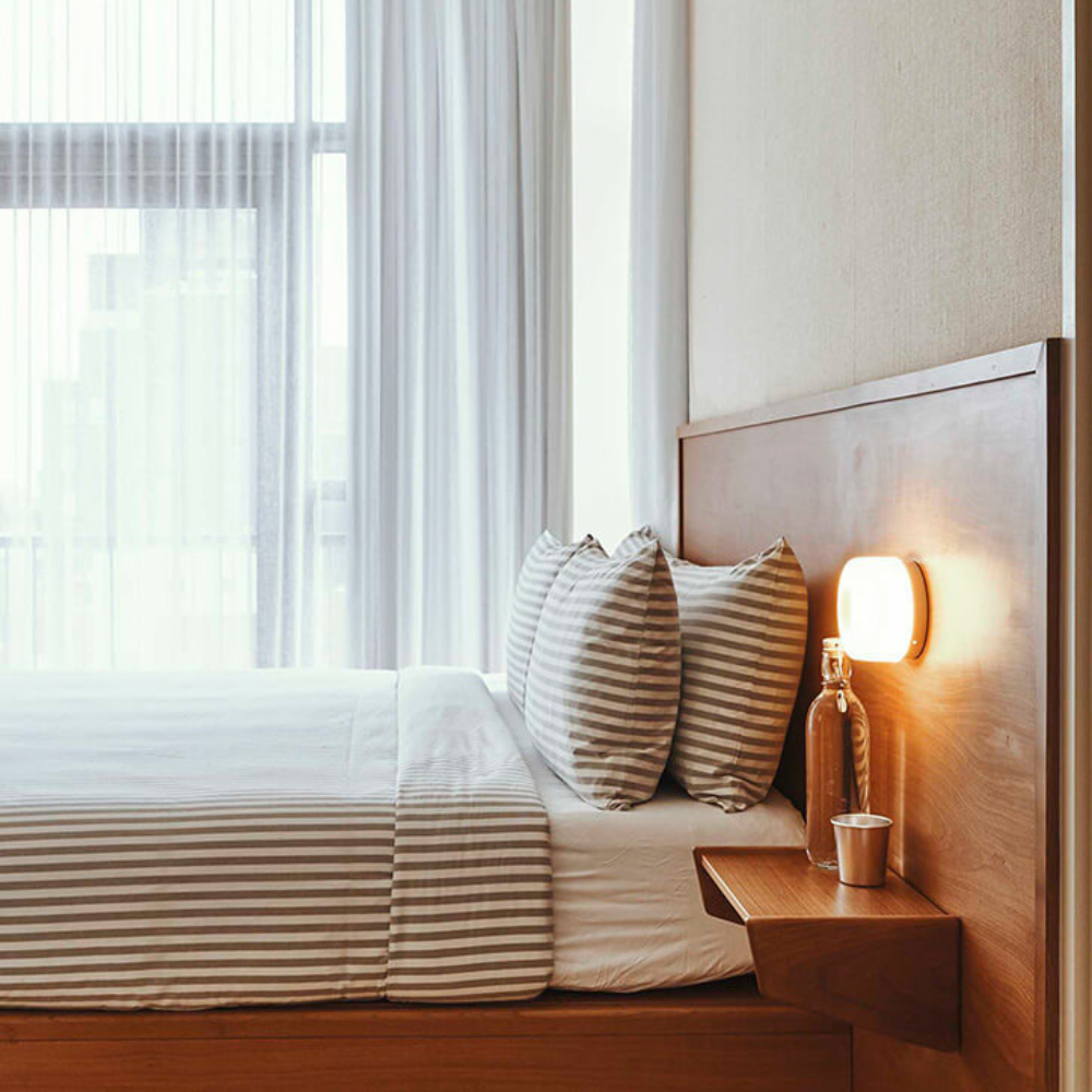 The Dimple Sconce by RBW with White Interior and Natural Anodized installed on a headboard. all-groups