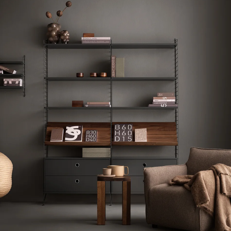 The Chest of Drawers from String Furniture in dark grey in a family room.