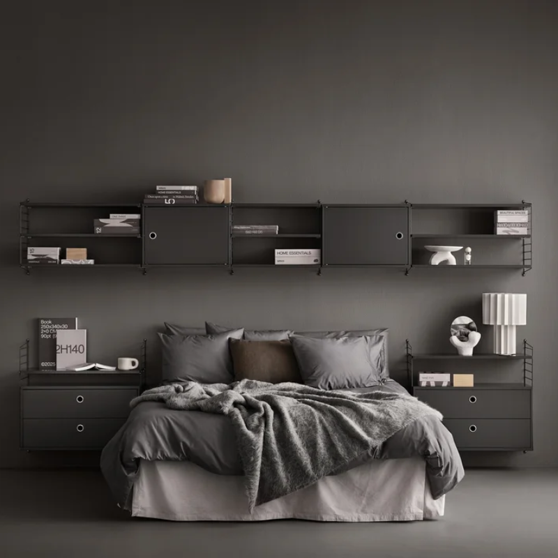 The shelves from String Furniture in dark grey in a bedroom.