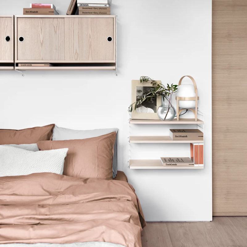 The String Pocket from String Furniture in ash and white in a primary bedroom.