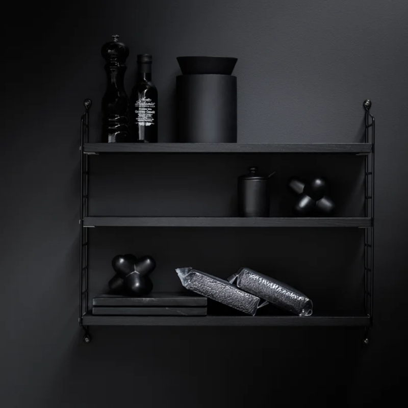 The String Pocket from String Furniture in black stained ash and black in a studio.