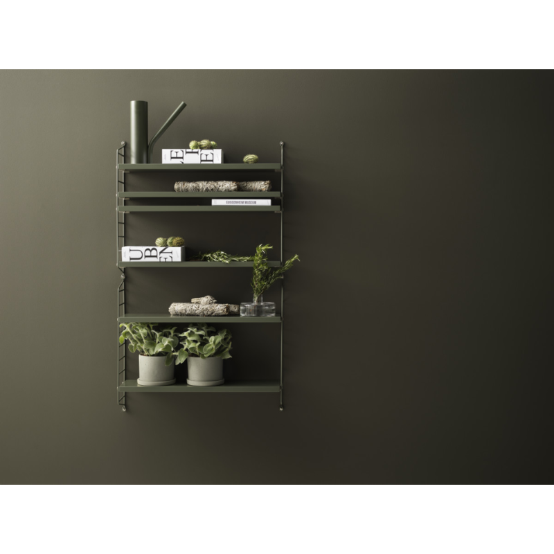 The String Pocket from String Furniture in sage in a family space.