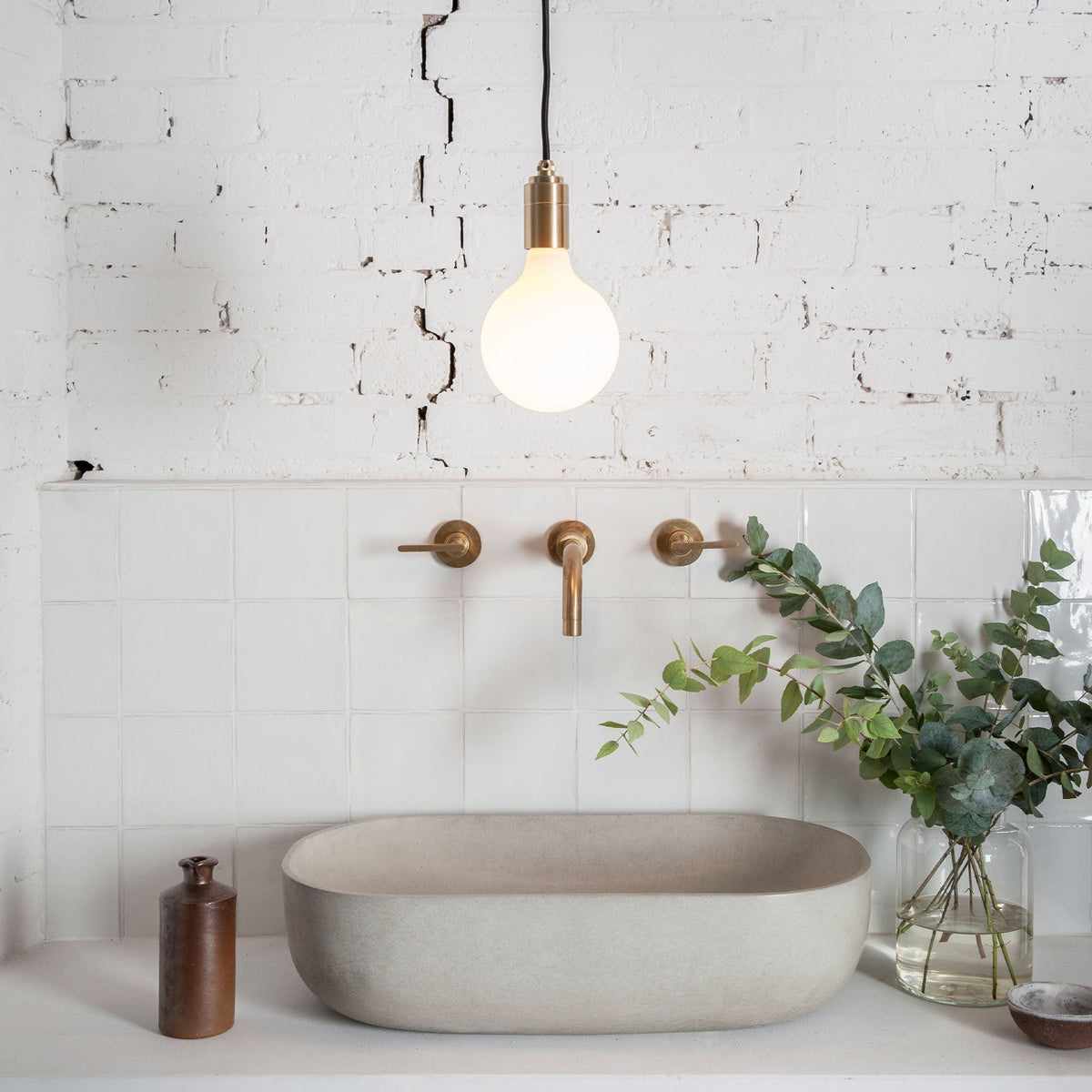The Porcelain III E26 LED Bulb by Tala Lighting in a pendant fitting over a bathroom sink.