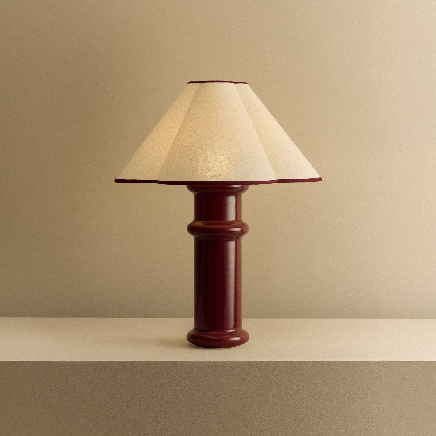 The Heath Table Lamp by Tala Lighting in Port Red turned on.