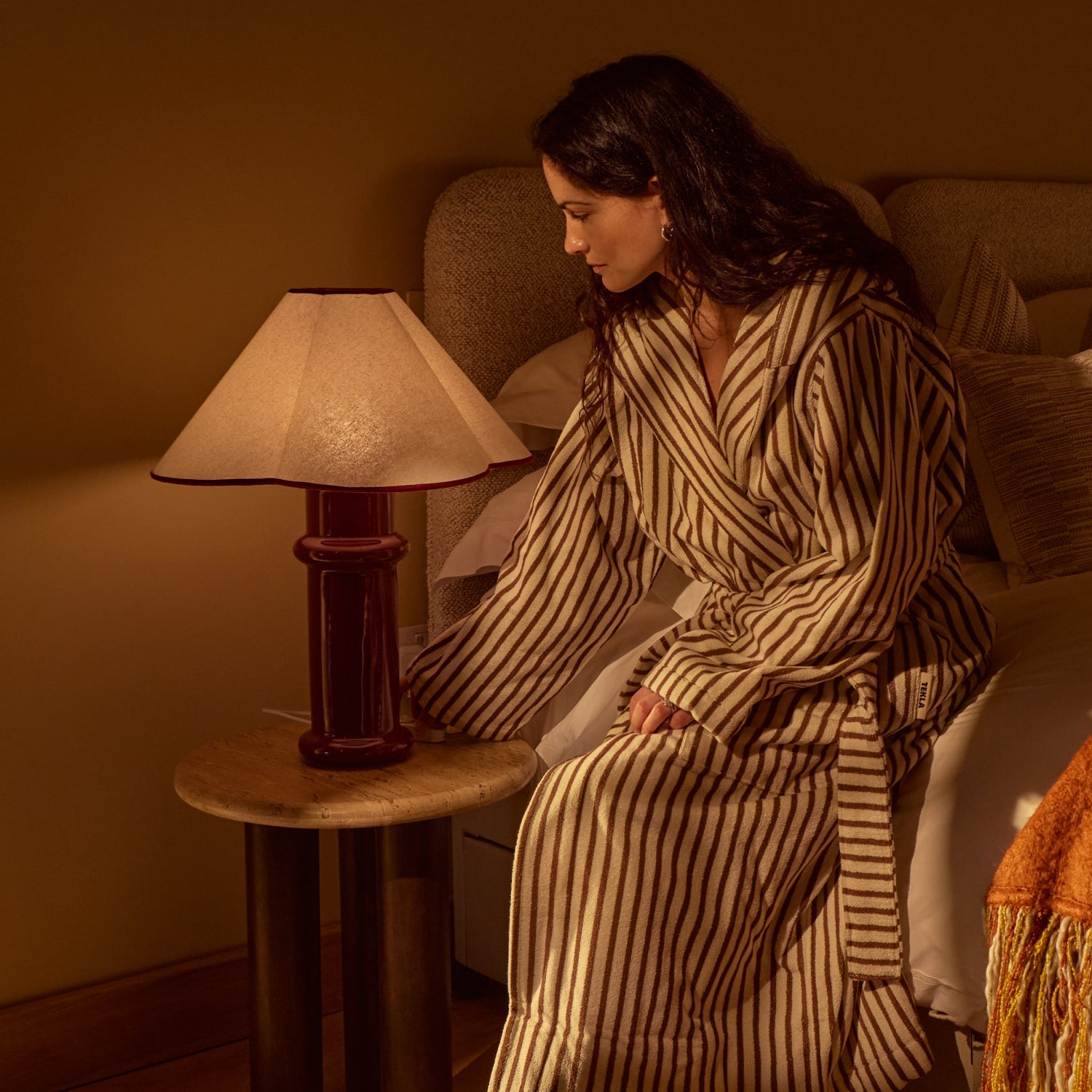 the Heath Table Lamp by Tala Lighting in Port Red used as a nightstand light.