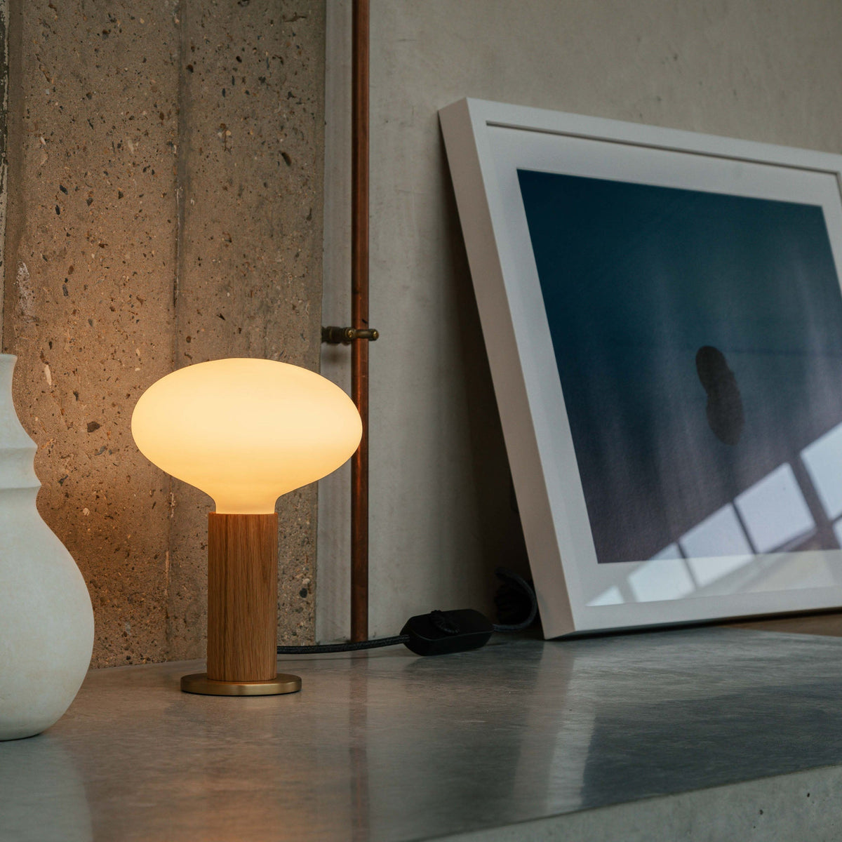 The Oval E26 Dim-to-Warm LED Bulb by Tala Lighting in a table base.