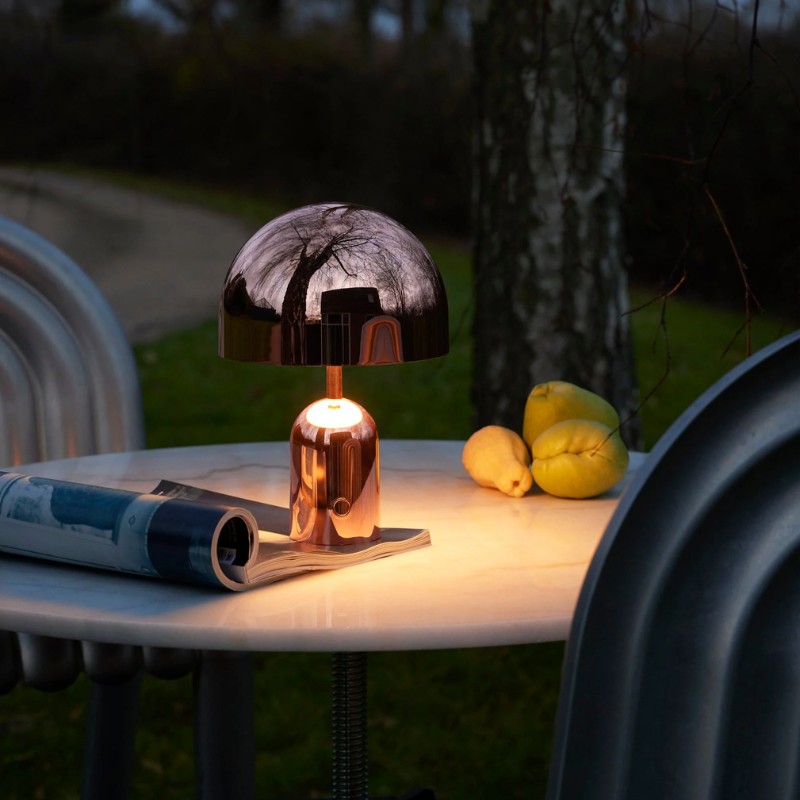 The Bell Portable LED from Tom Dixon in copper in a garden.