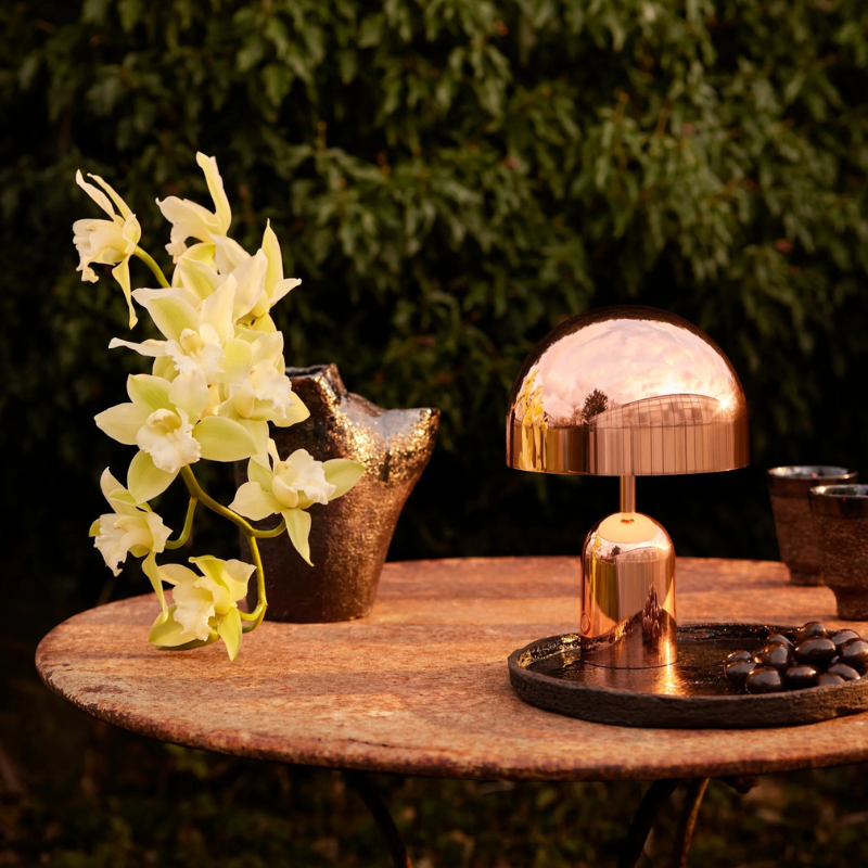 The Bell Portable LED from Tom Dixon in copper in an outdoor dining area.