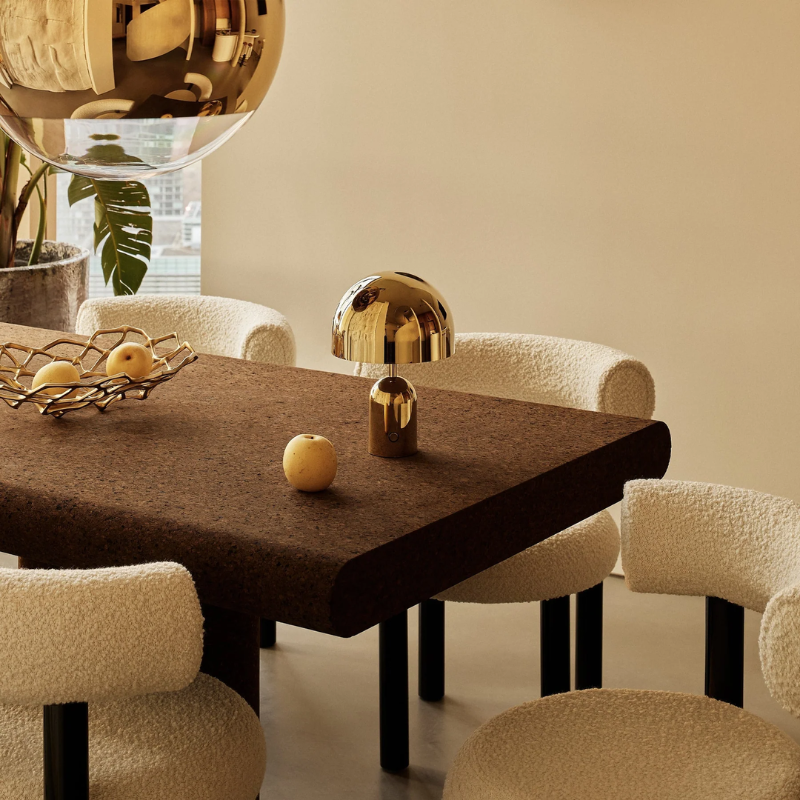 The Bell Portable LED from Tom Dixon in gold in a dining room.