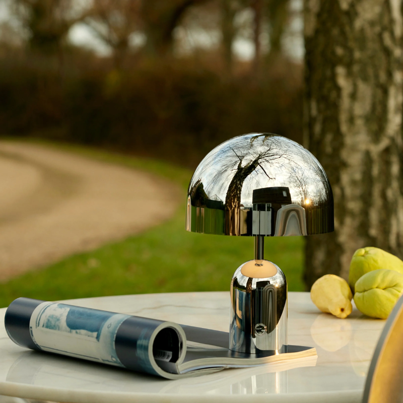 The Bell Portable LED from Tom Dixon in silver on a cafe table.