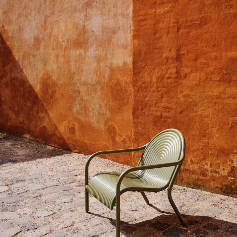 The Groove Outdoor Lounge Chair by Tom Dixon in Moss on a patio.