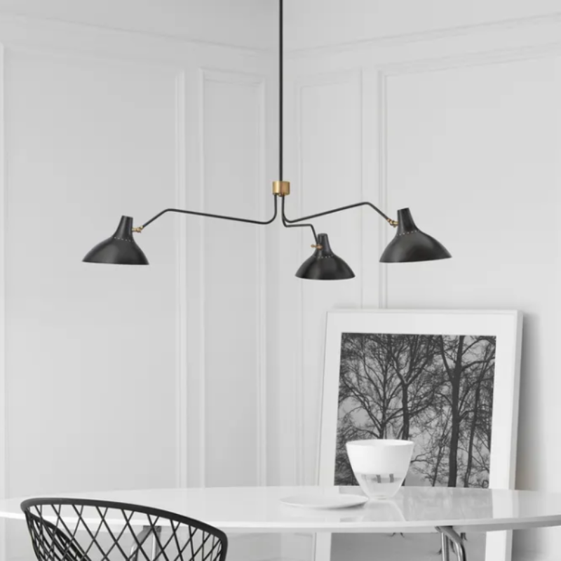 The black and brass Charlton Large Triple Arm Chandelier from Visual Comfort & Co in a dining room.