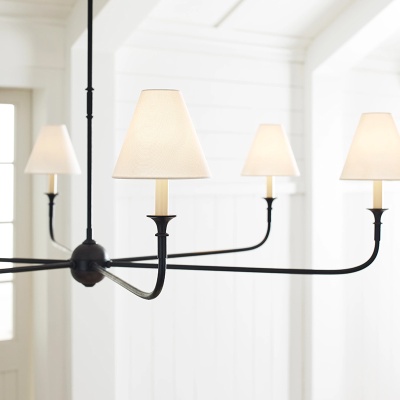 The Piaf Grande Chandelier from Visual Comfort & Co. in aged iron and ebonized oak in a living room.