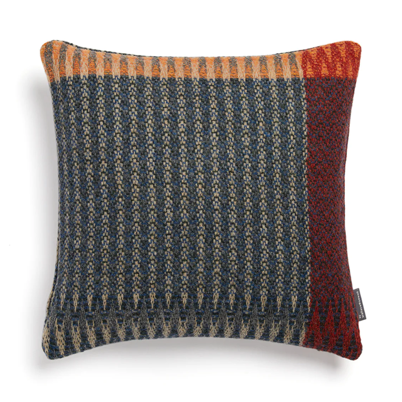 The Cairngorm Shetland Tweed Cushion is a textured pillow with orange, red, and blue pattern.