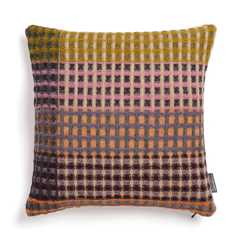 The Kew Cushion by Wallace and Sewell is made of natural shetland wool. Pink and yellow accents.