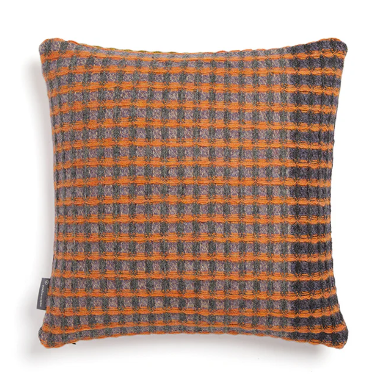 The Kew Cushion by Wallace and Sewell is made of natural shetland wool. Orange accents with check pattern.