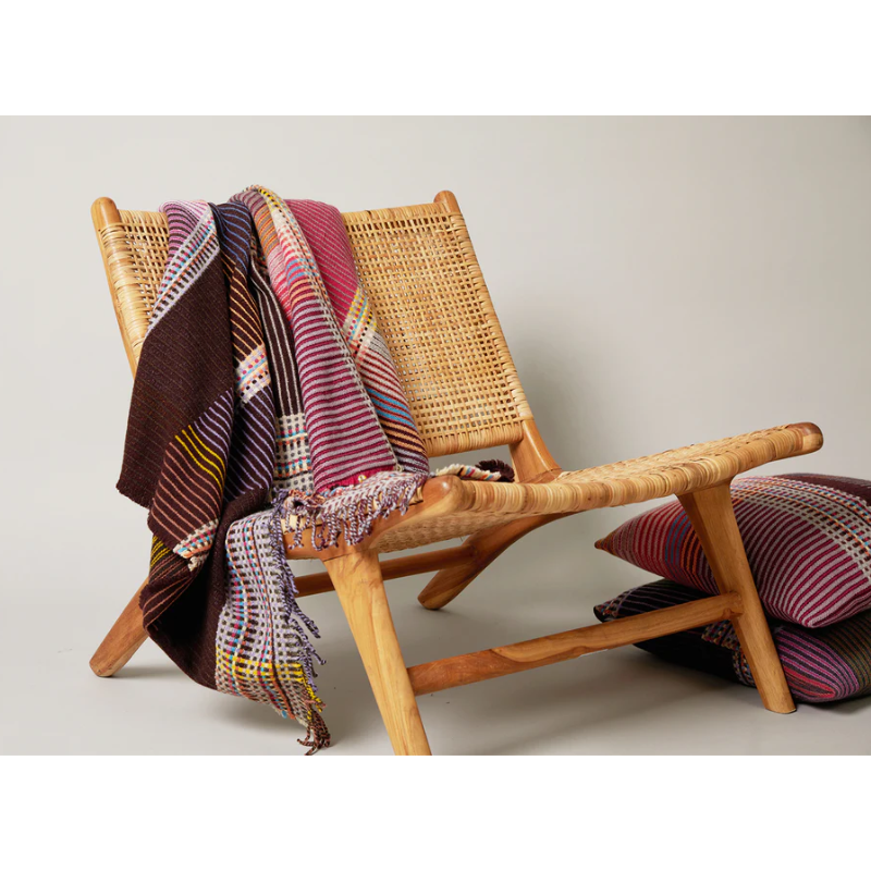 The Sophia Throw by Wallace & Sewell with matching throw pillow on a lounge chair.