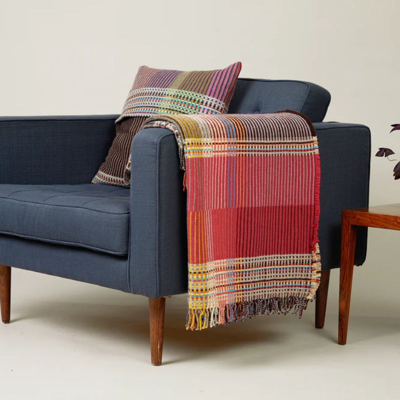 The Sophia Throw by Wallace & Sewell with matching throw pillow on an armchair.