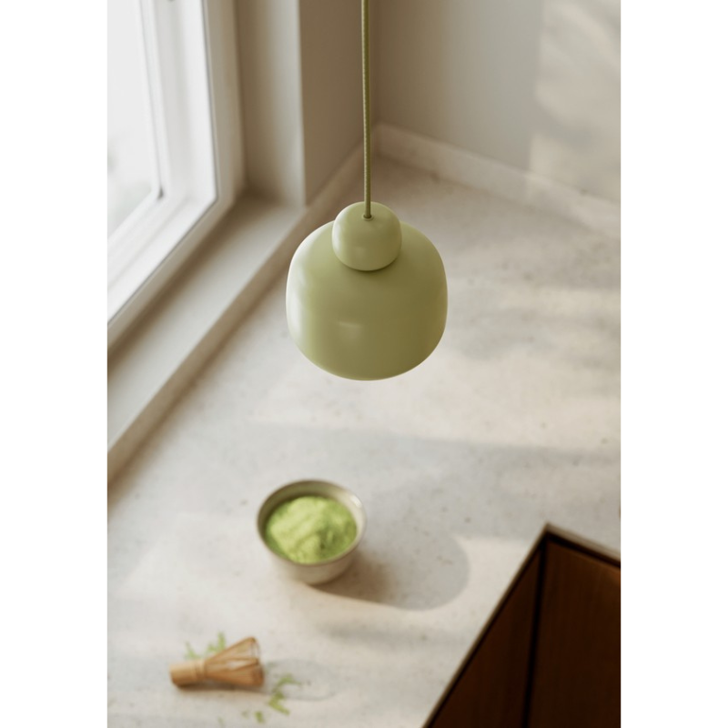 The small Stone Pendant from Woud in matcha over a kitchen counter.