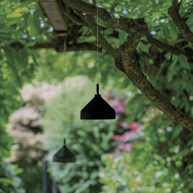 The black Amelie Pro Hanging Lamp from Zafferano in a front yard.