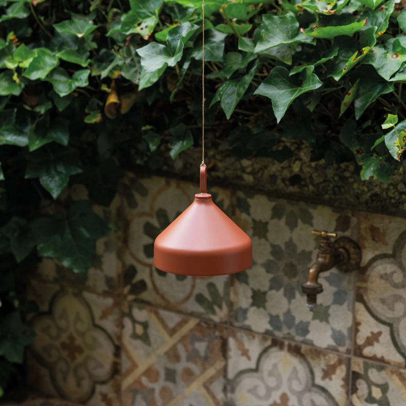 The terracotta Amelie Pro Hanging Lamp from Zafferano in a courtyard.