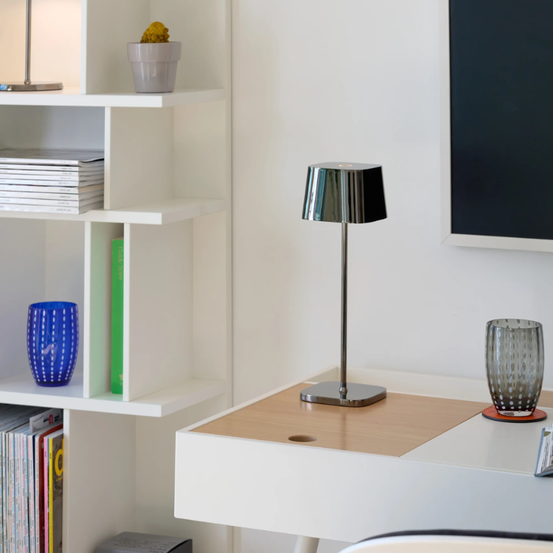 The black chrome Ofelia Pro cordless lamp from Zafferano in a home office.