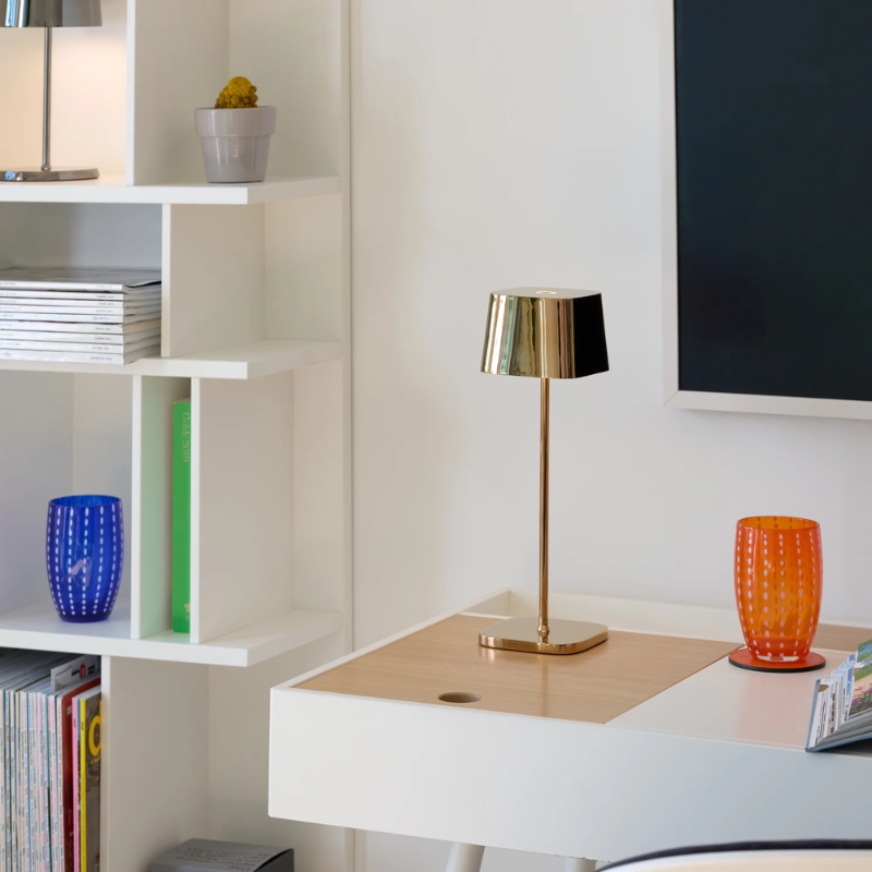 The rose gold Ofelia Pro cordless lamp from Zafferano in a tv room.