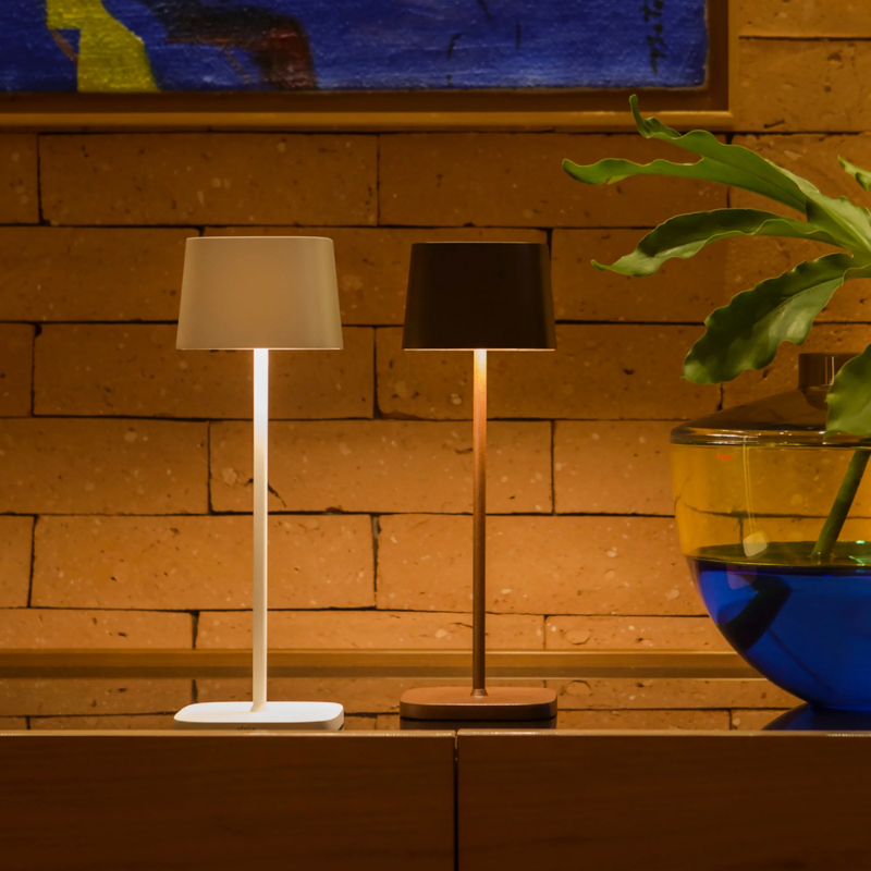 The rust Ofelia Pro cordless lamp from Zafferano in a living area.