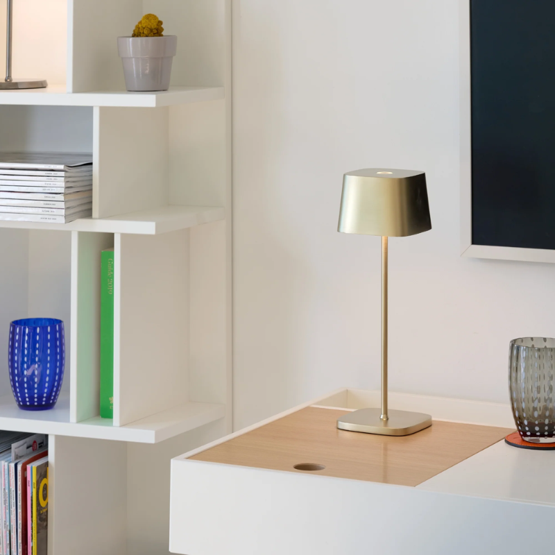 The satin brass Ofelia Pro cordless lamp from Zafferano in a den.