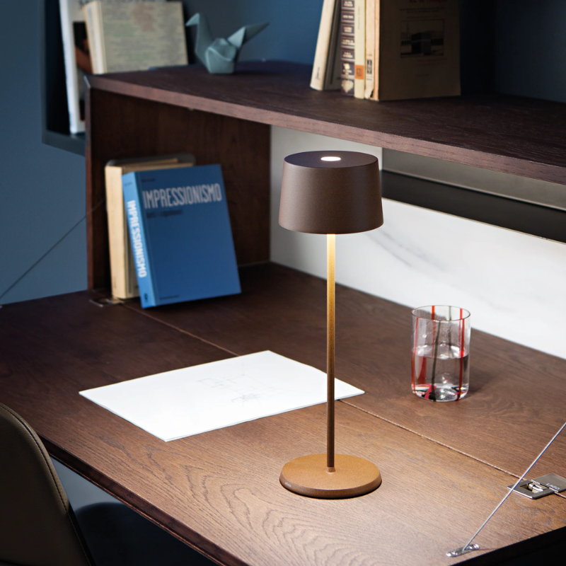 The rust Olivia Pro cordless lamp from Zafferano in a home office.