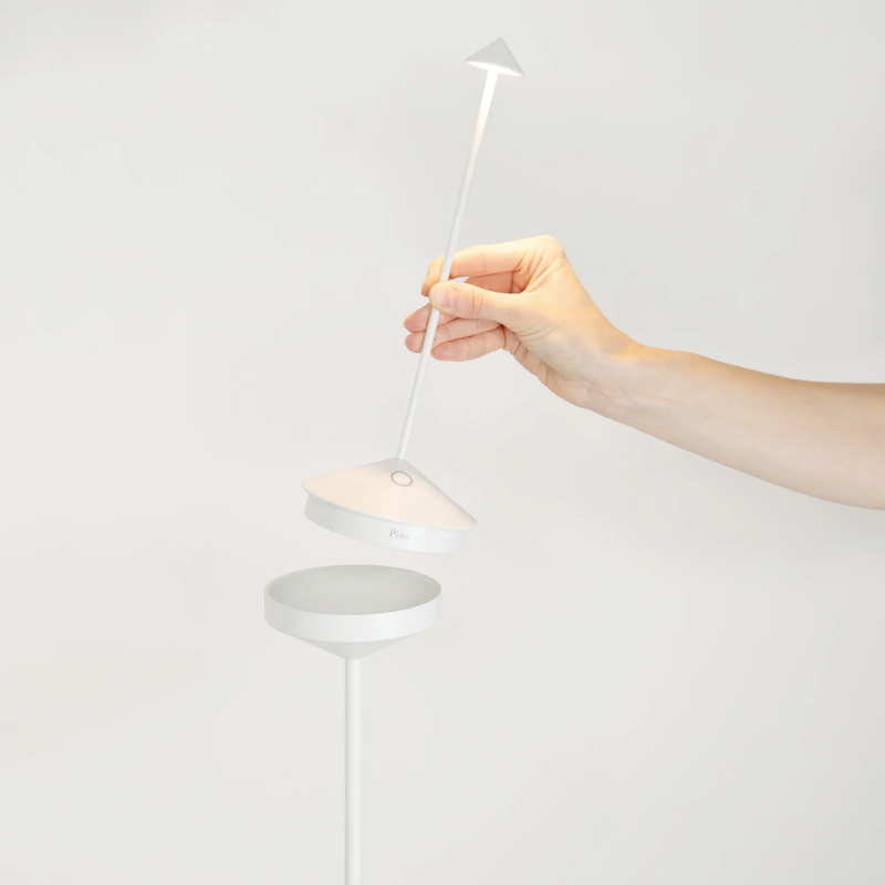 The white Pina Pro Floor Stand from Zafferano is handheld in a lifestyle image.