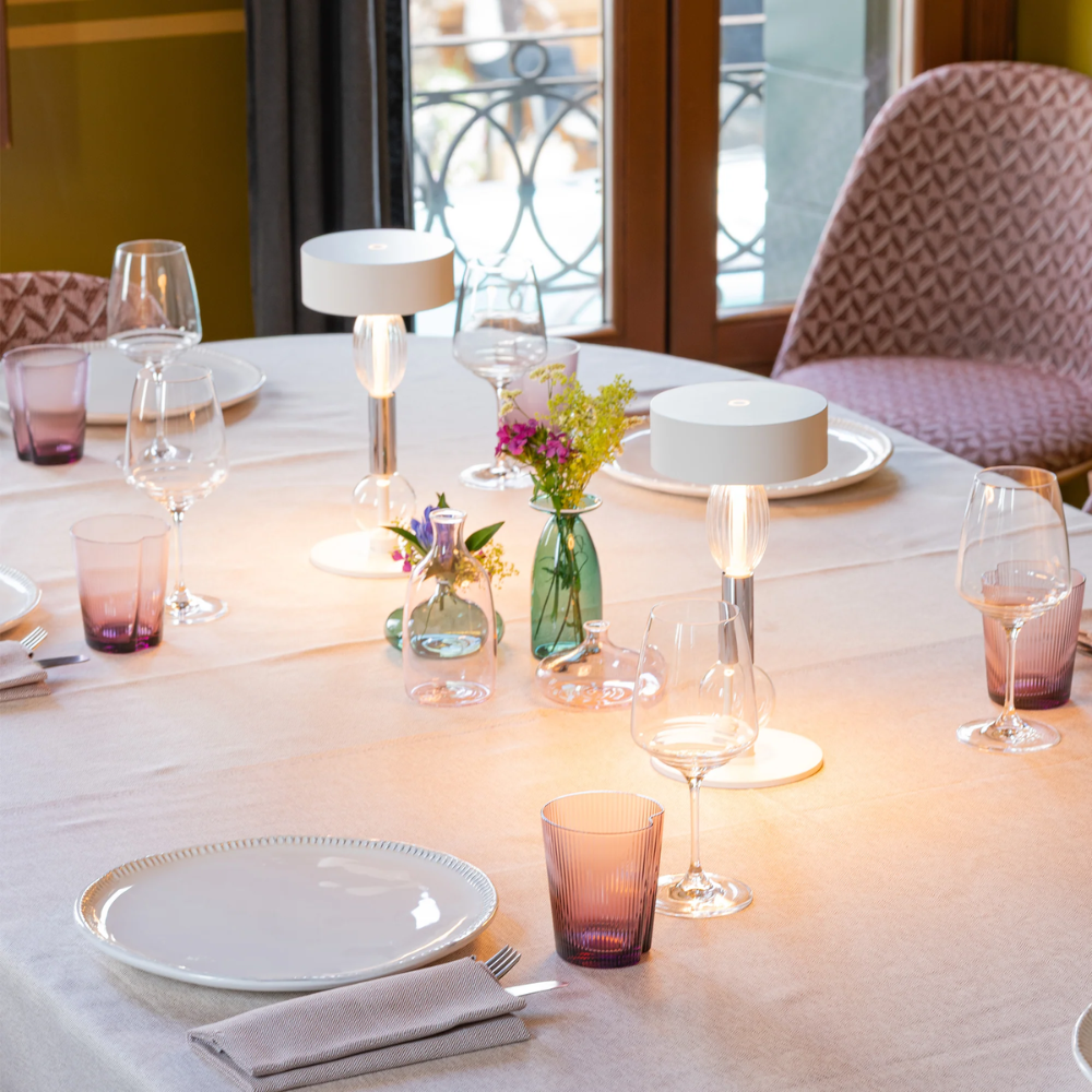 The white with clear and gray glass Royal Family Wi-Fi Table Lamp from Zafferano on a dining table.