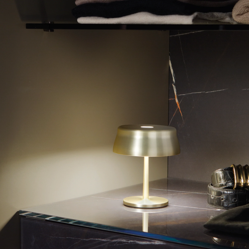 The anodized gold Sister Light Mini Wi-Fi Table Lamp from Zafferano in a commercial space.