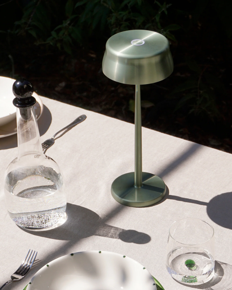 The anodized green Sister Light Wi-Fi Table Lamp from Zafferano is in the outdoor dining area.