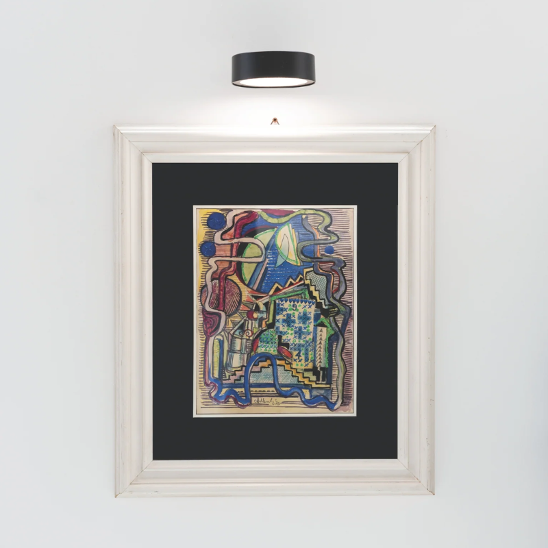 The black Super O Wall Spotlight from Zafferano illuminating artwork.