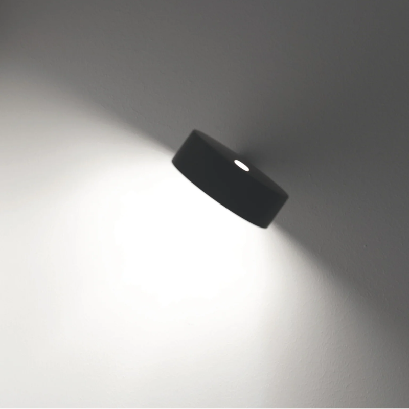 The black Super O Wall Spotlight from Zafferano in a living room.