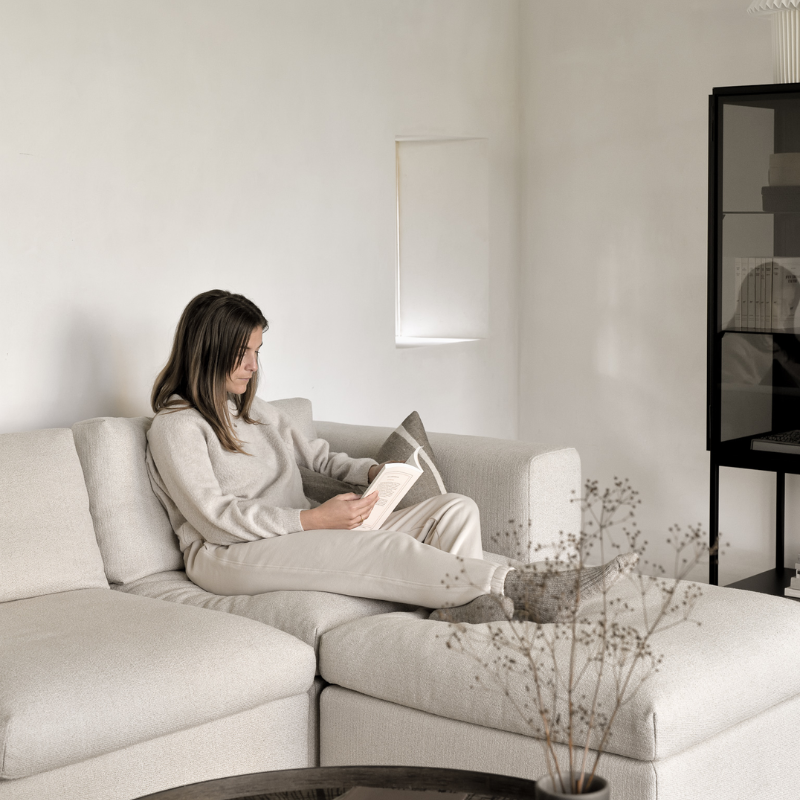 The Mellow End Seater from Ethnicraft in the family room with a woman reading a book.