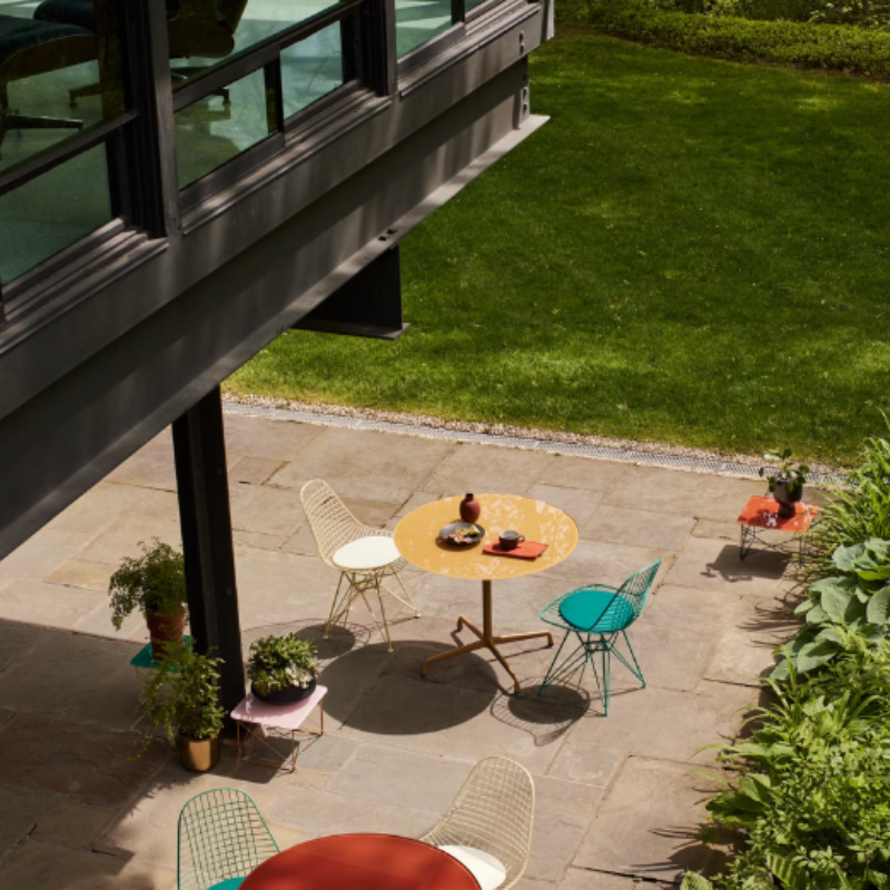 The Eames Dining Table from Herman Miller, designed by Herman Miller x Hay in a courtyard.