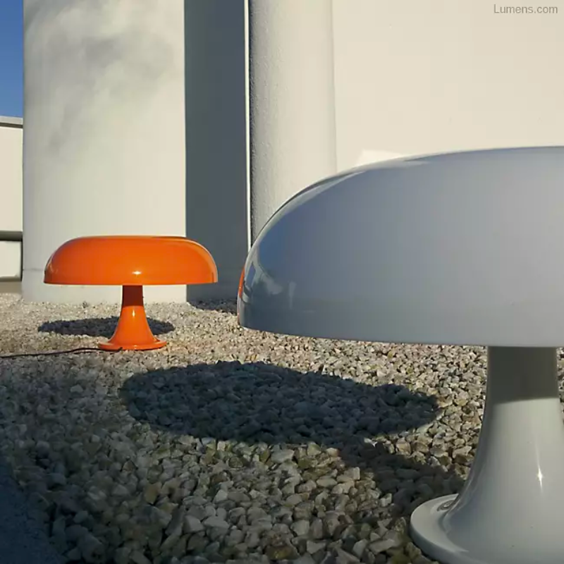 The Nesso Table Lamp from Artemide in orange in a bedroom.